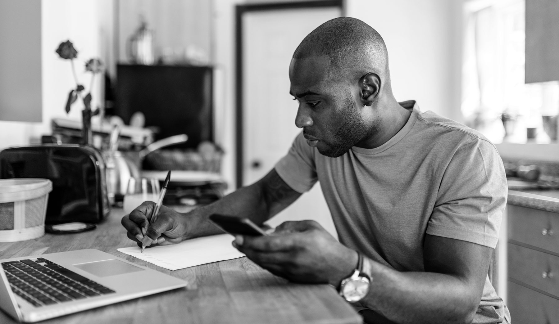 Man writing on paper in front of computer