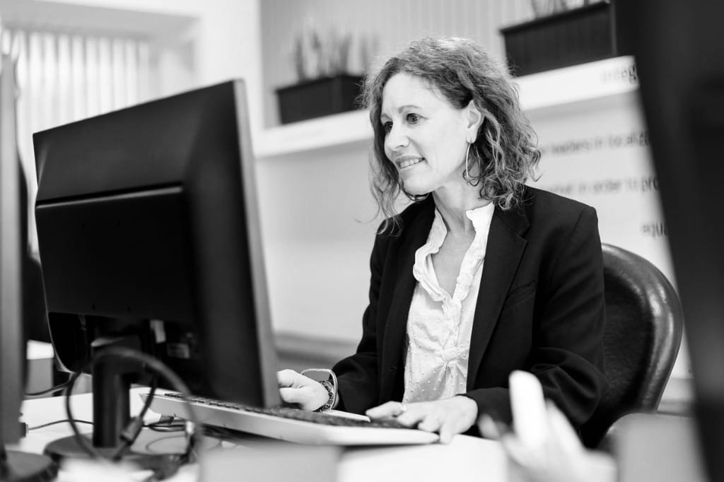 An executive smiles as she reads information on her computer